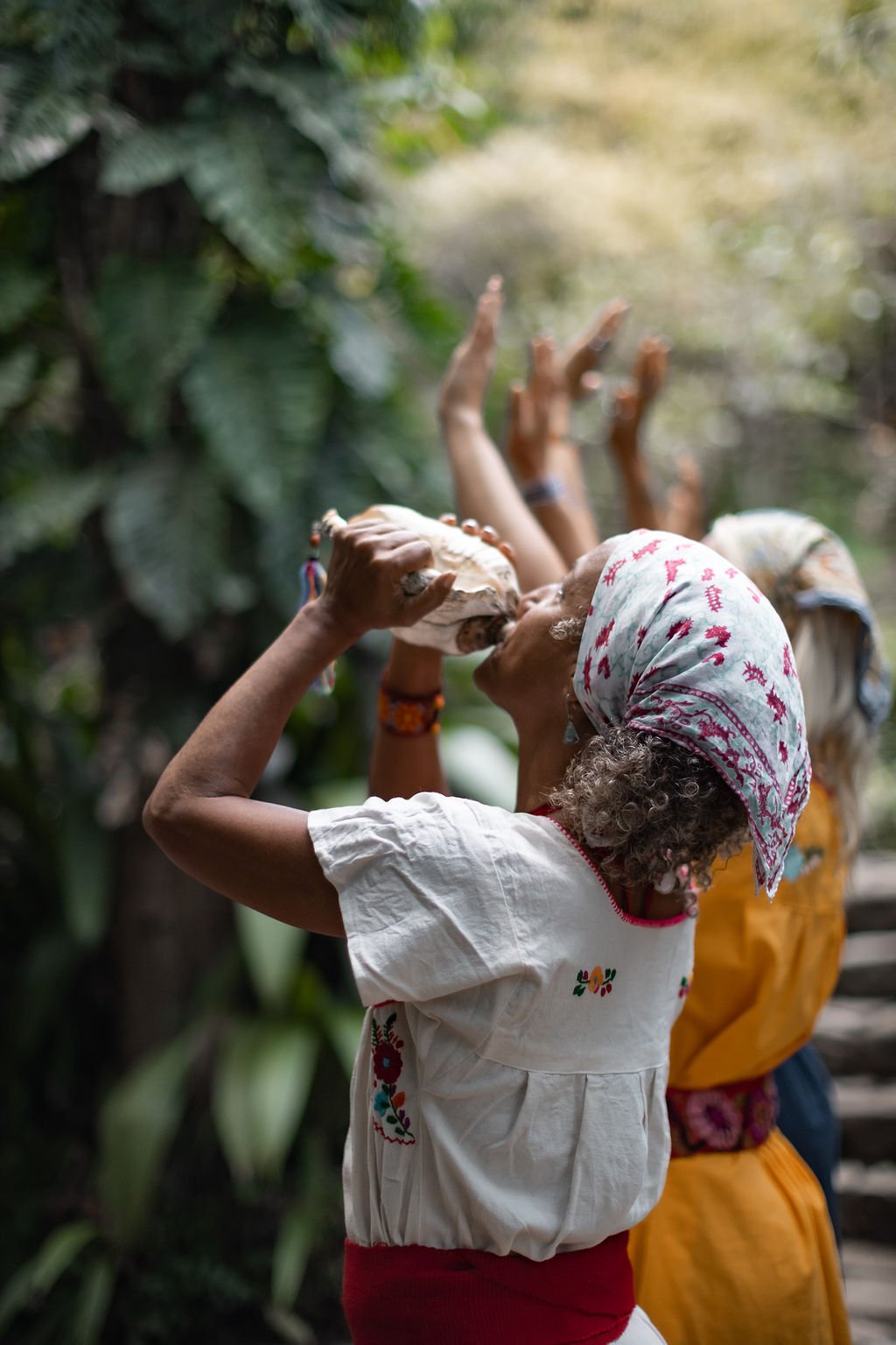 A woman raising a conch shell in ceremony
