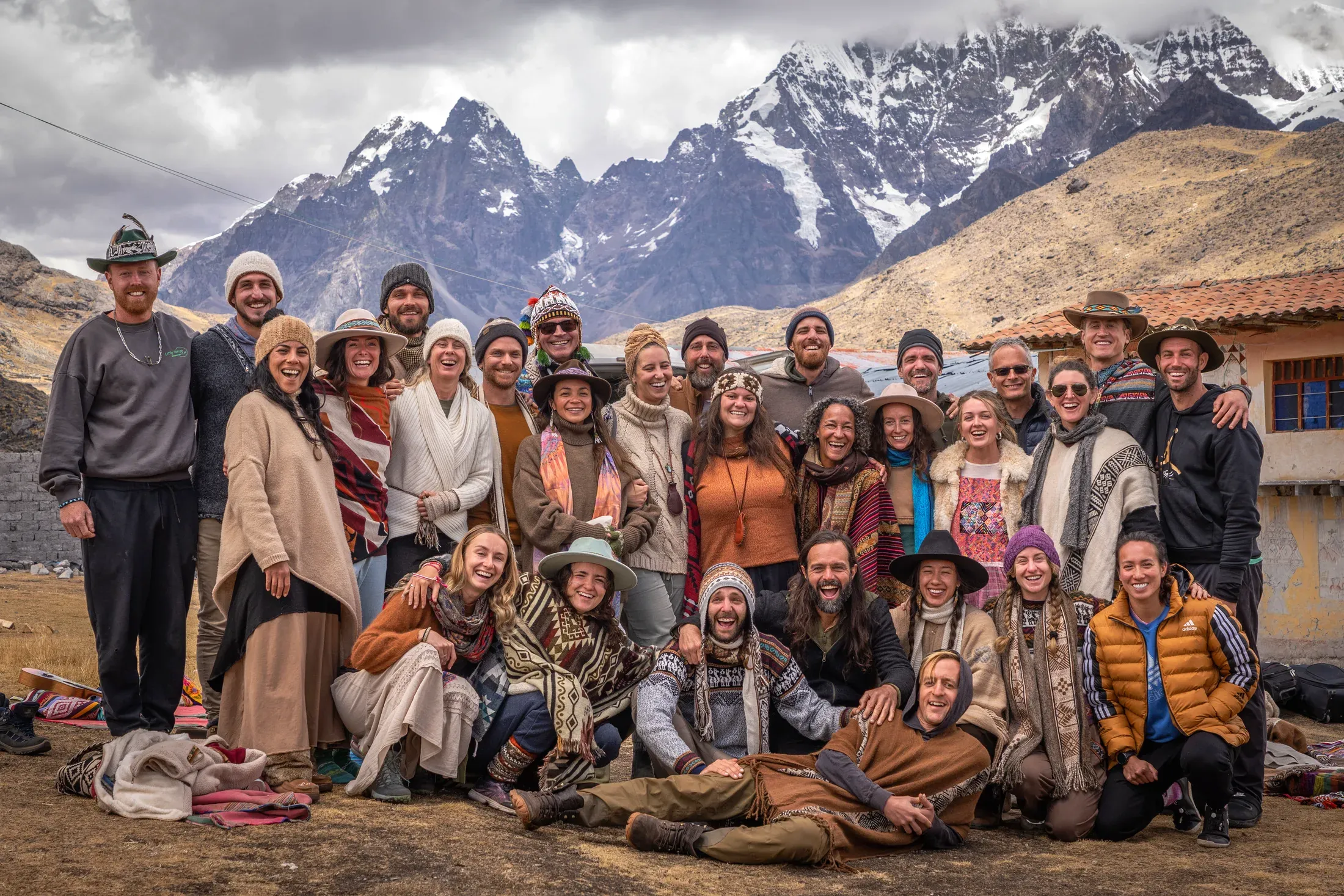 The whole pilgrimage group gathered for a portrait in an Andean village with snow peaks behind