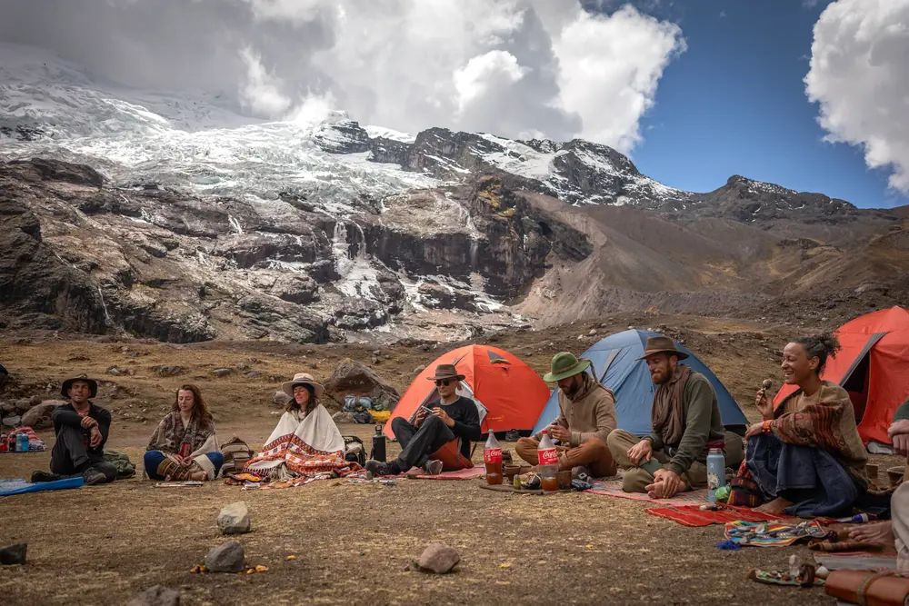Tents and a circle of pilgrims sharing a meal at camp below the glacier