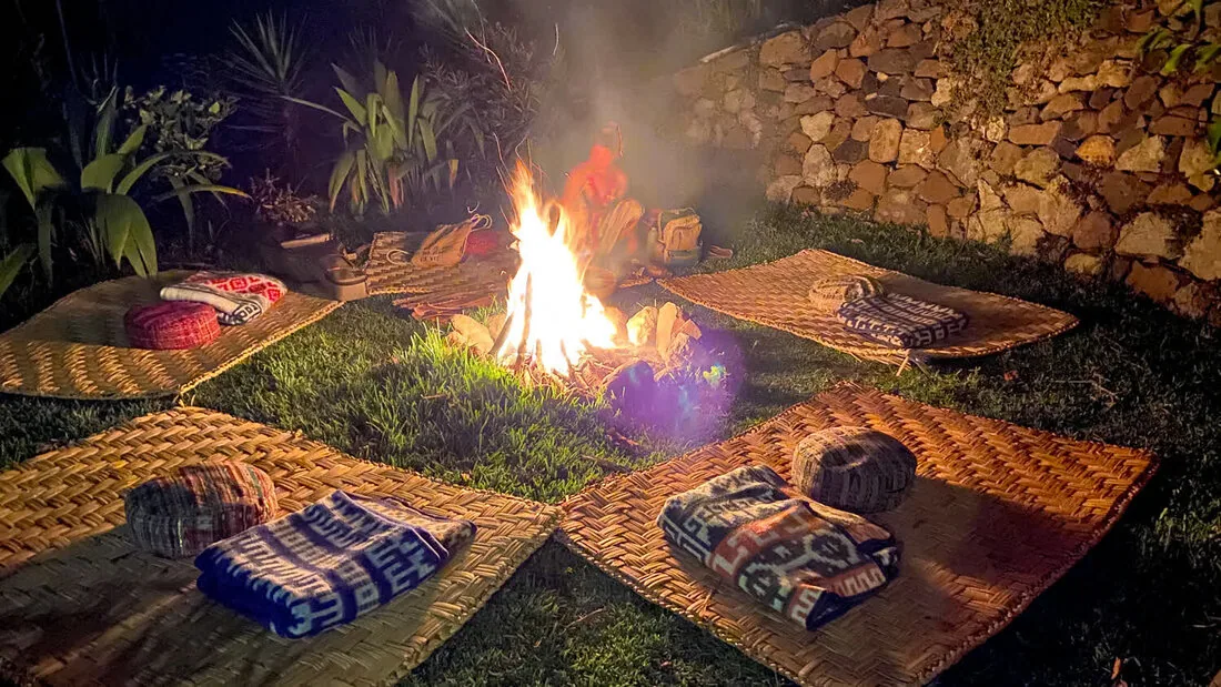 A ceremonial fire at night surrounded by woven mats