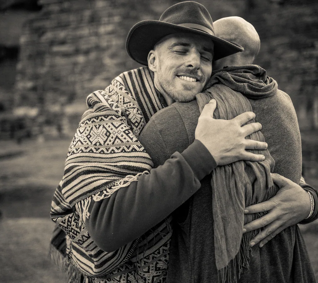 Coby, in a hat and poncho, sharing a warm embrace